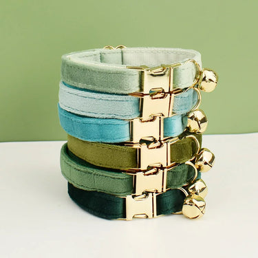 KittyNook Cat Co. Velvet Cat Collars in green and blue, with gold buckles, shown on a green backdrop.